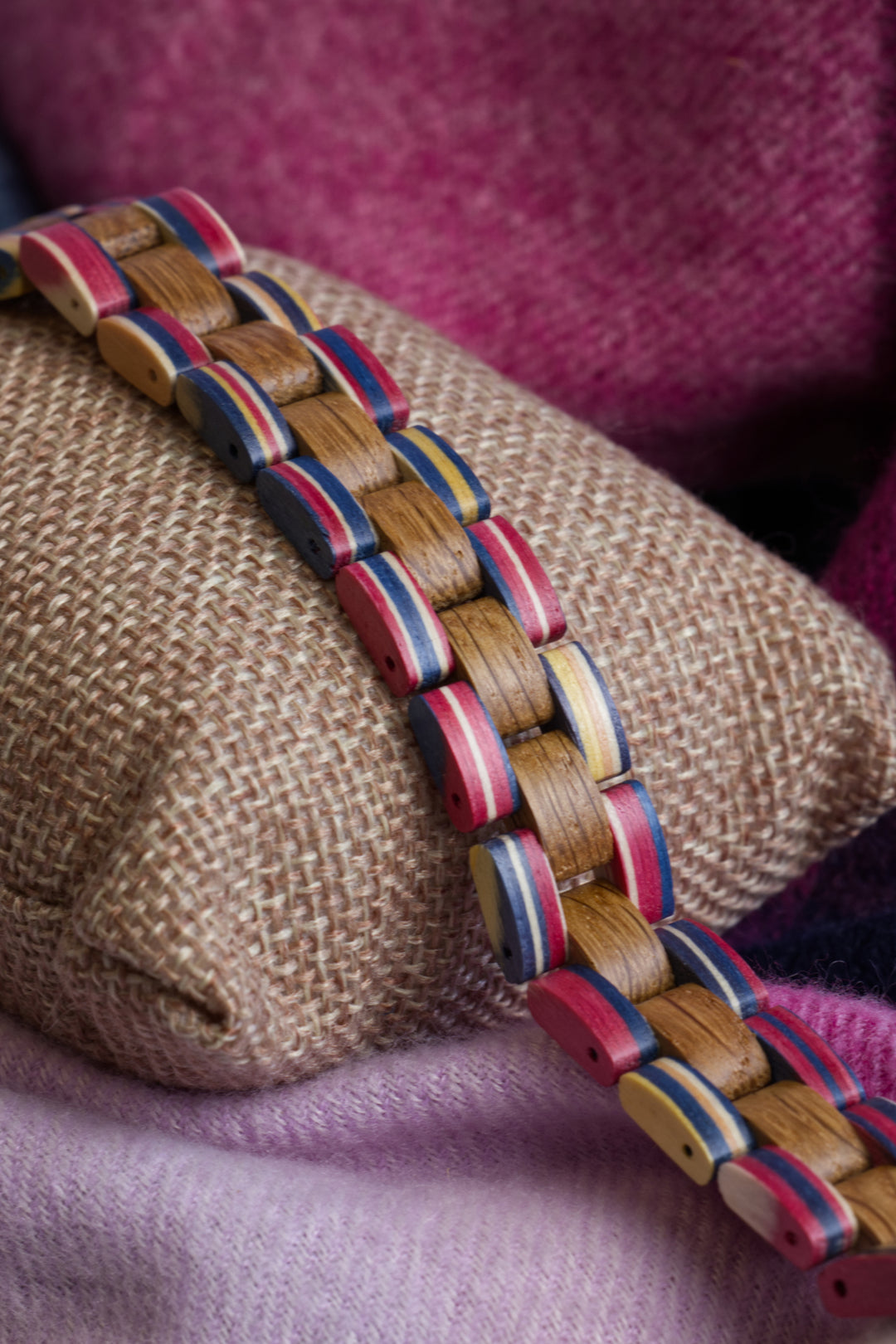 Amalfi wooden bracelet with red, blue and yellow accents on a cushion - The Wood Look