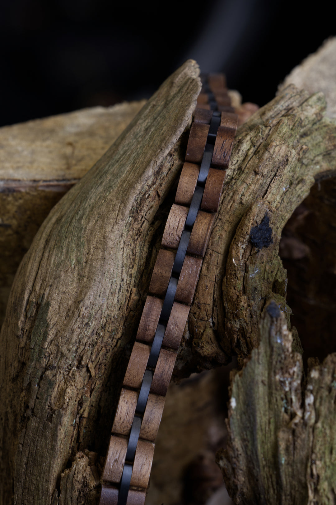 Aspen walnut and black steel bracelet draped over weathered wood - The Wood Look