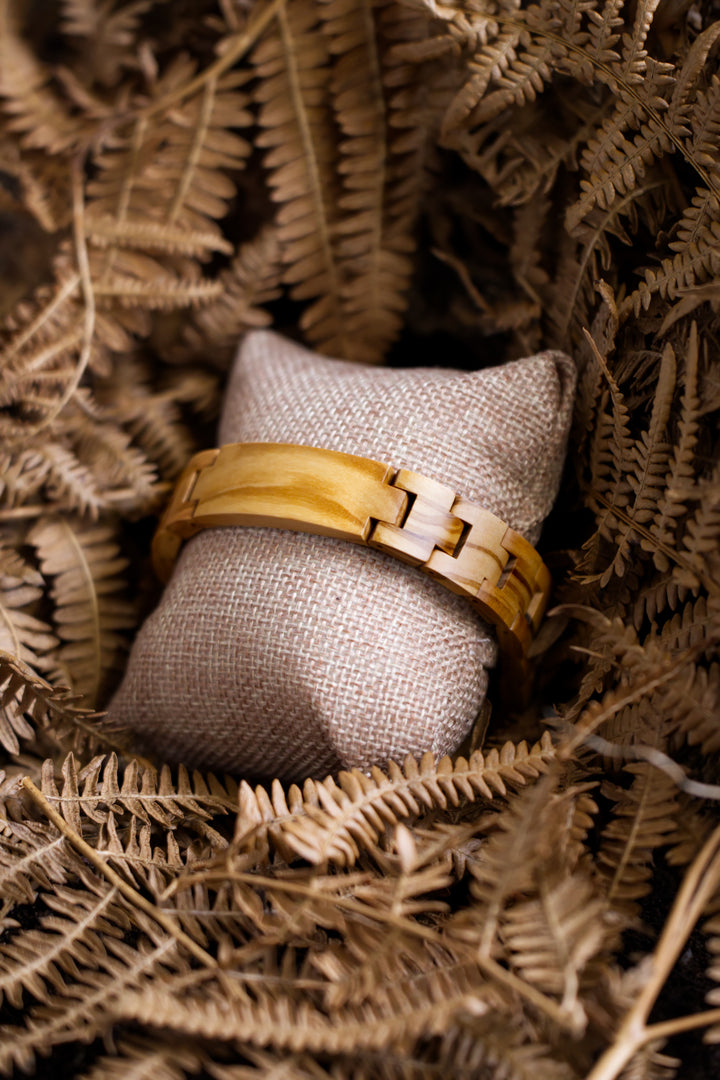 Carmel light olive wood bracelet on a cushion with dried ferns - The Wood Look