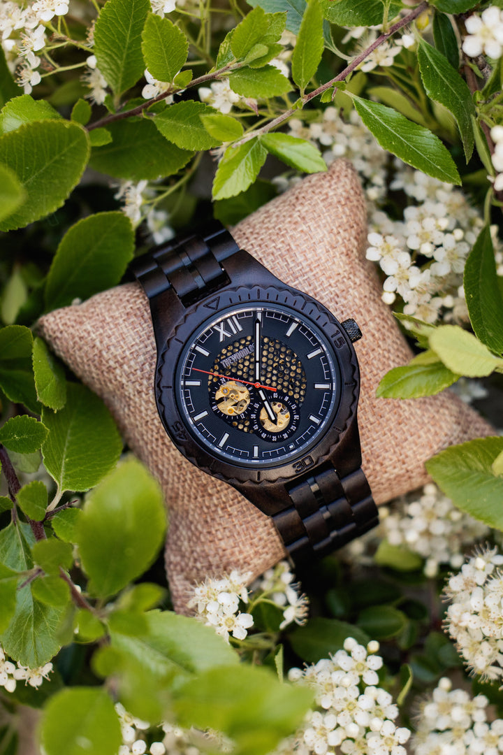 Detroit ebony mechanical watch with a black skeleton dial on a cushion among white blossom - The Wood Look