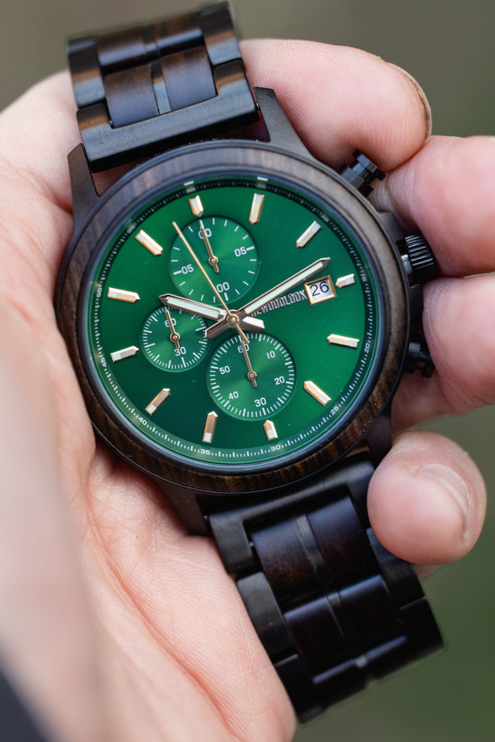 Hand holding the Gothenburg dark wood watch, showing the green chronograph dial up close - The Wood Look