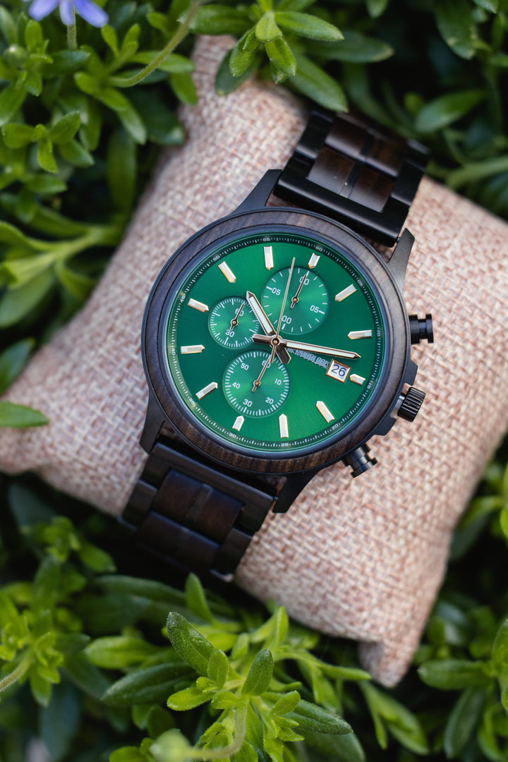 Gothenburg dark wood chronograph watch with a green dial on a cushion among greenery - The Wood Look