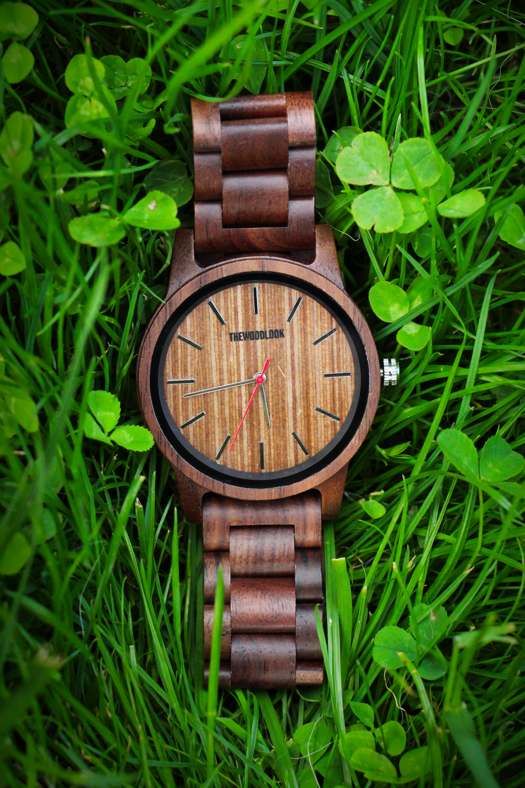 Warsaw minimalist walnut wooden watch with a wooden dial lying on grass and clover - The Wood Look